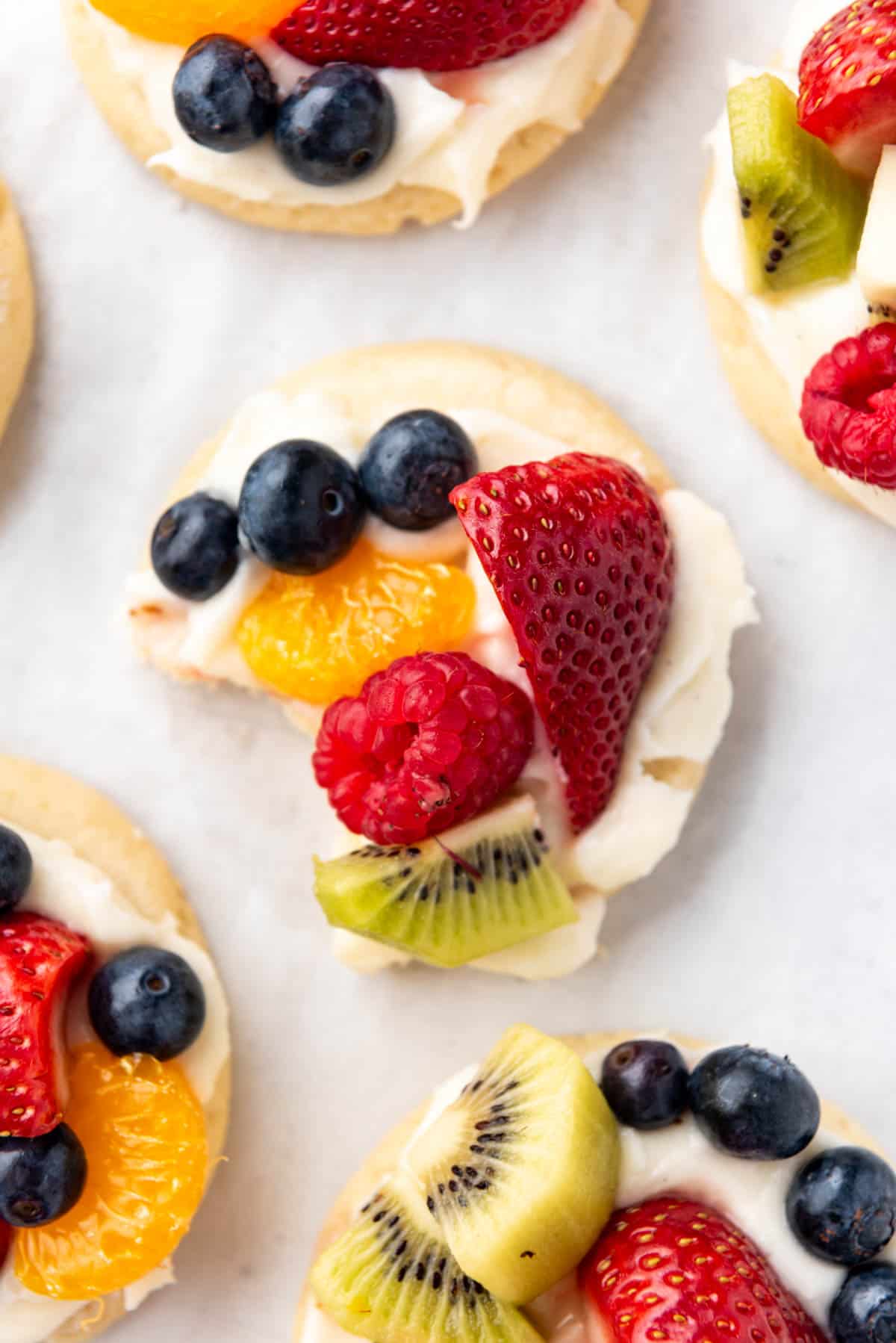 An overhead image of a fruit pizza cookie with a bite taken out of it.