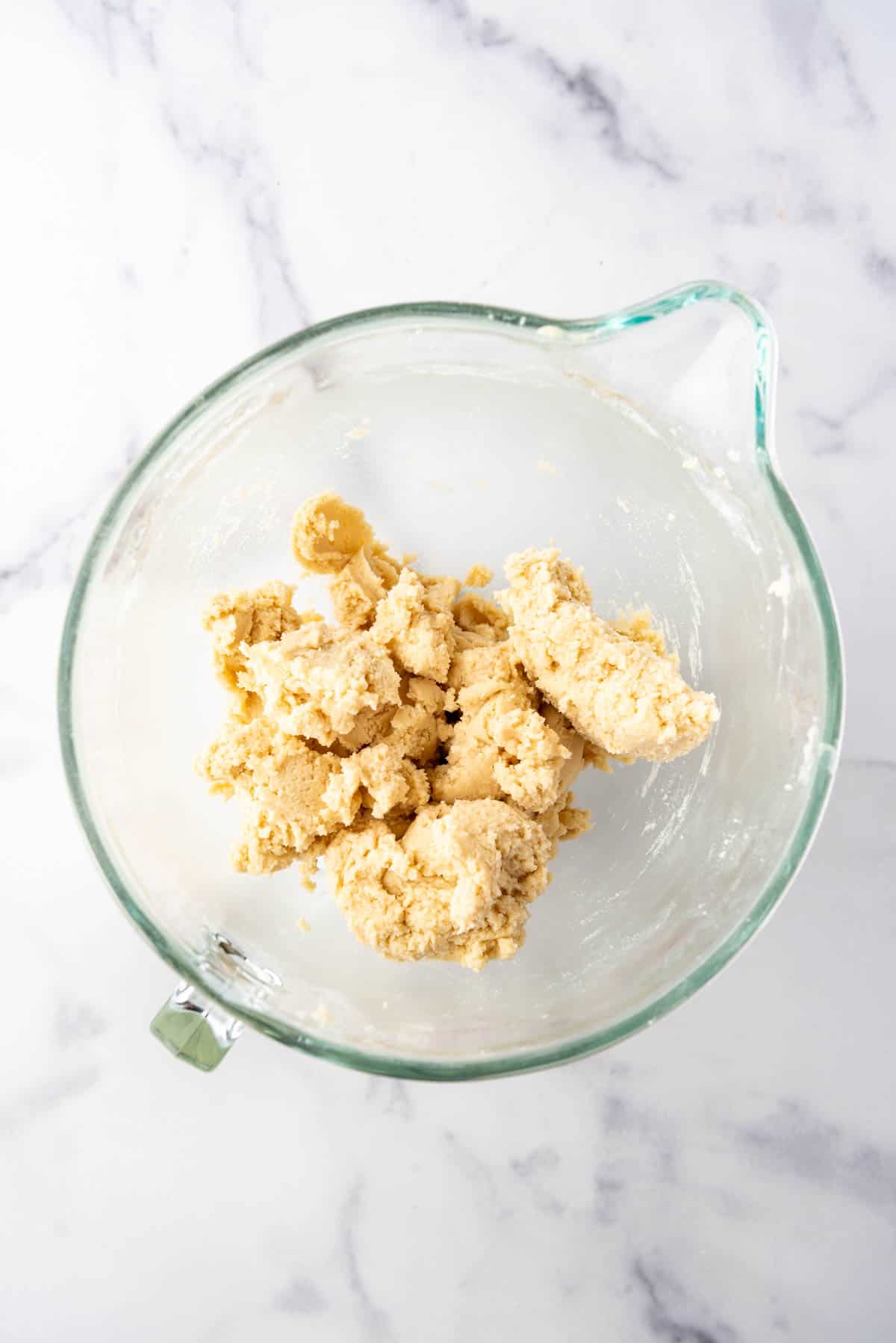 An overhead image of a glass mixing bowl of sugar cookie dough.