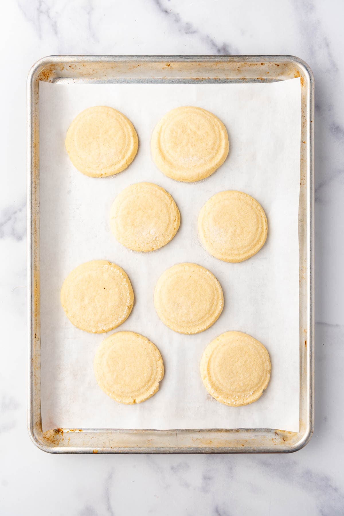 Baked sugar cookies on a baking sheet lined with parchment paper.