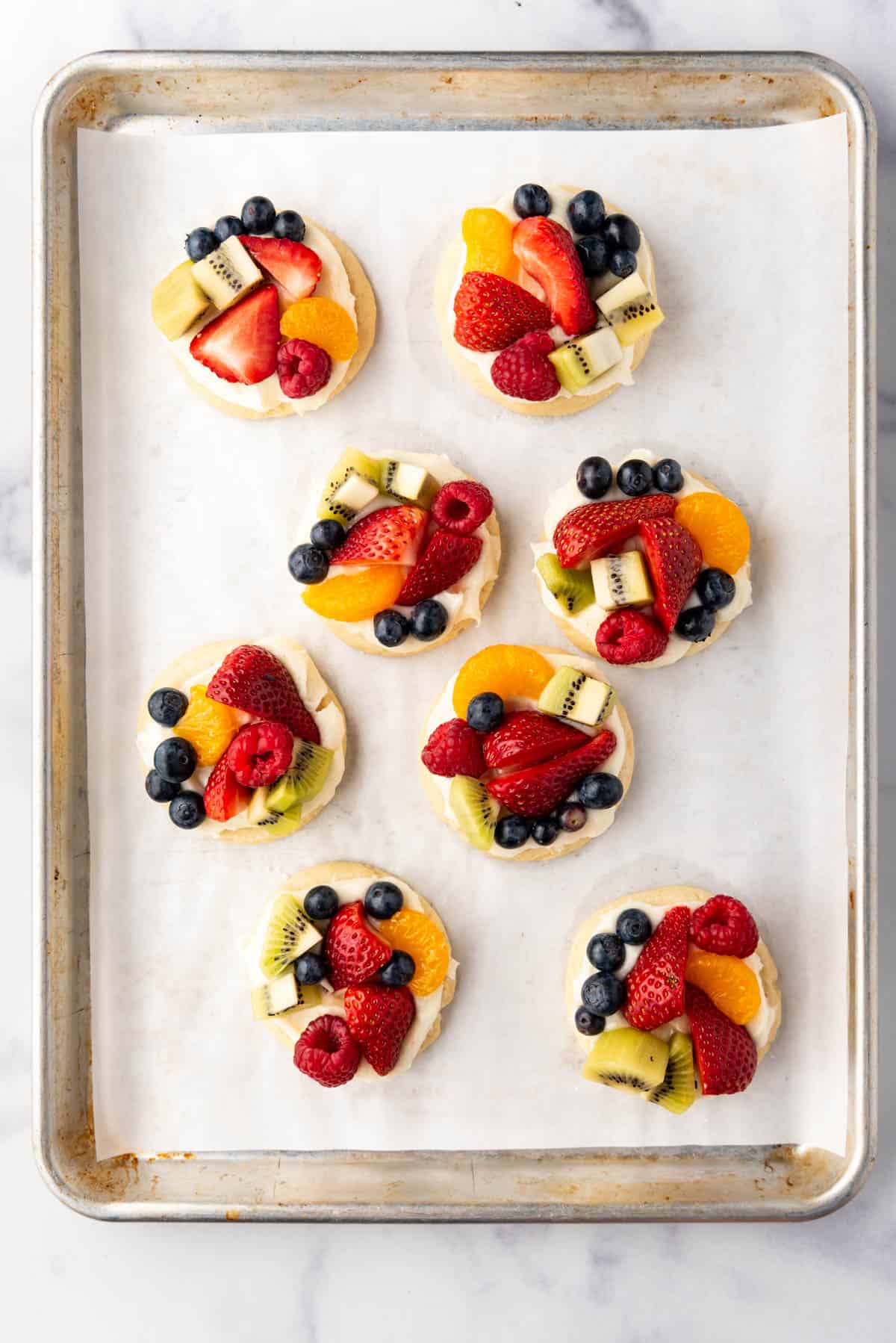 Fruit pizza cookies on a baking sheet.