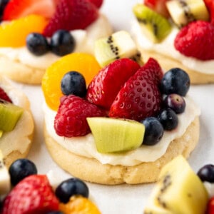 A close image of a fruit pizza cookie topped with cream cheese frosting and lots of fresh fruit.