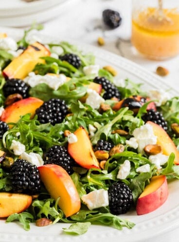 An image of a grilled peach salad on a large white plate.