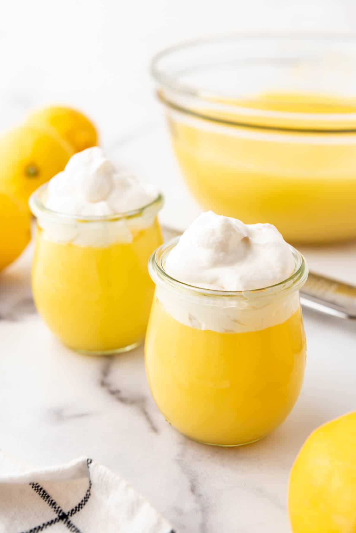 Two glass jars of lemon pudding with whipped cream.