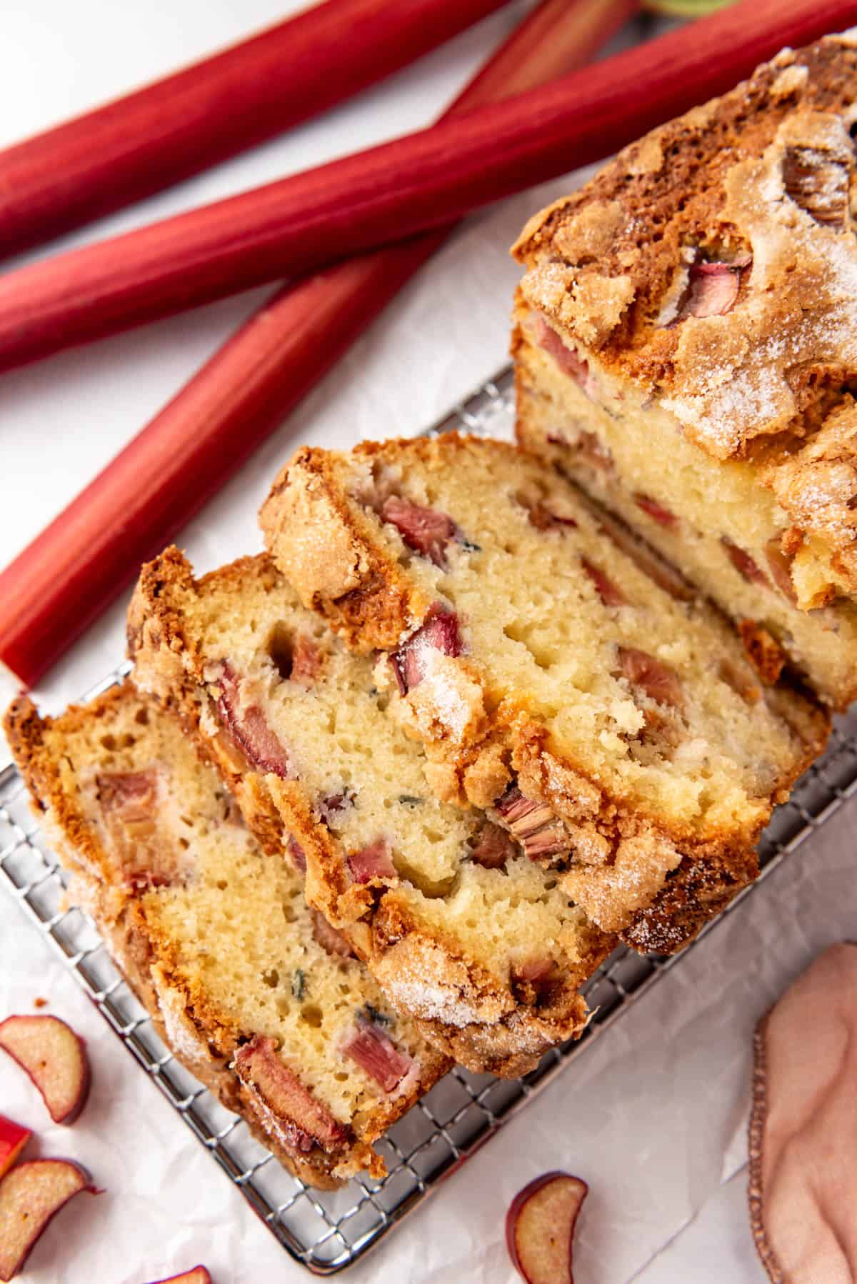 An overhead image of slices of rhubarb bread next to stalks of rhubarb.