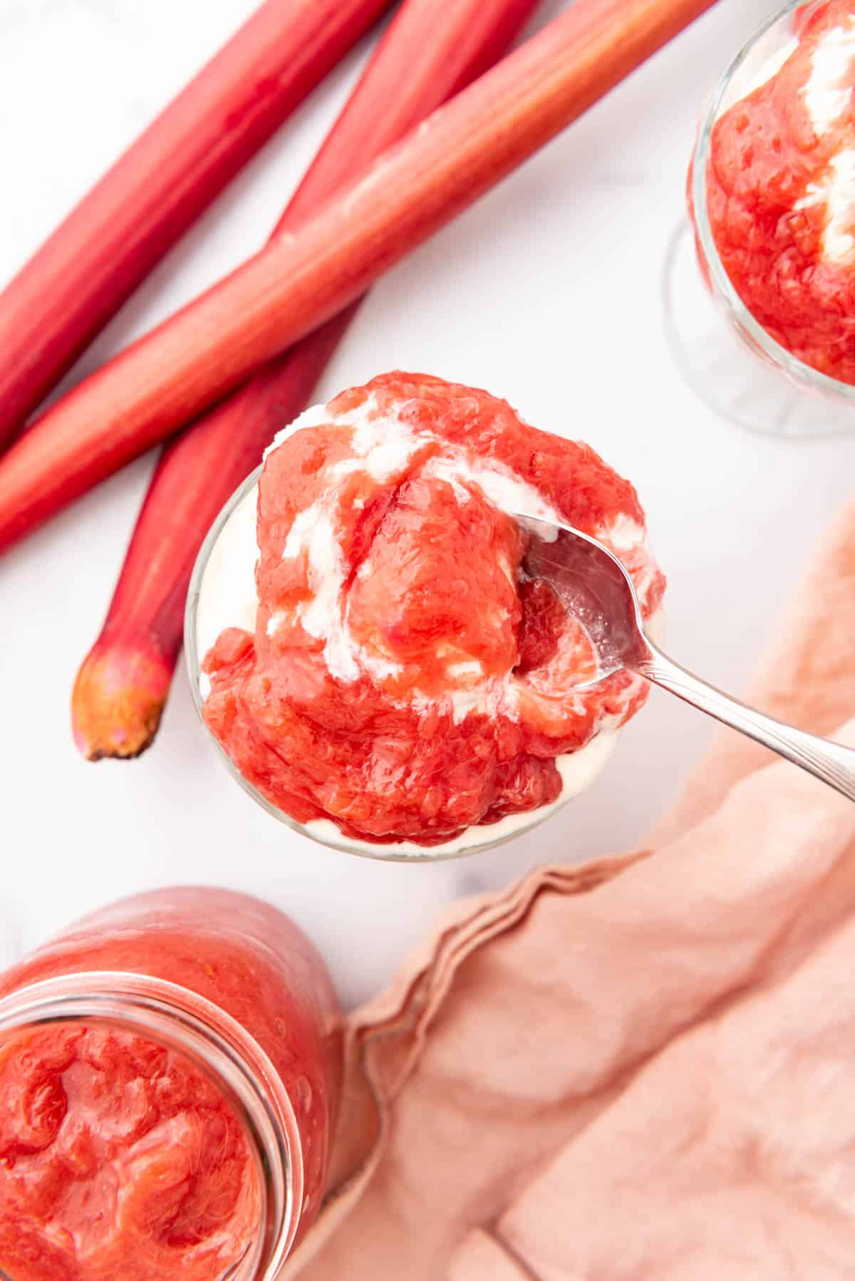 An overhead image of a spoon in a bowl of vanilla ice cream with rhubarb sauce.