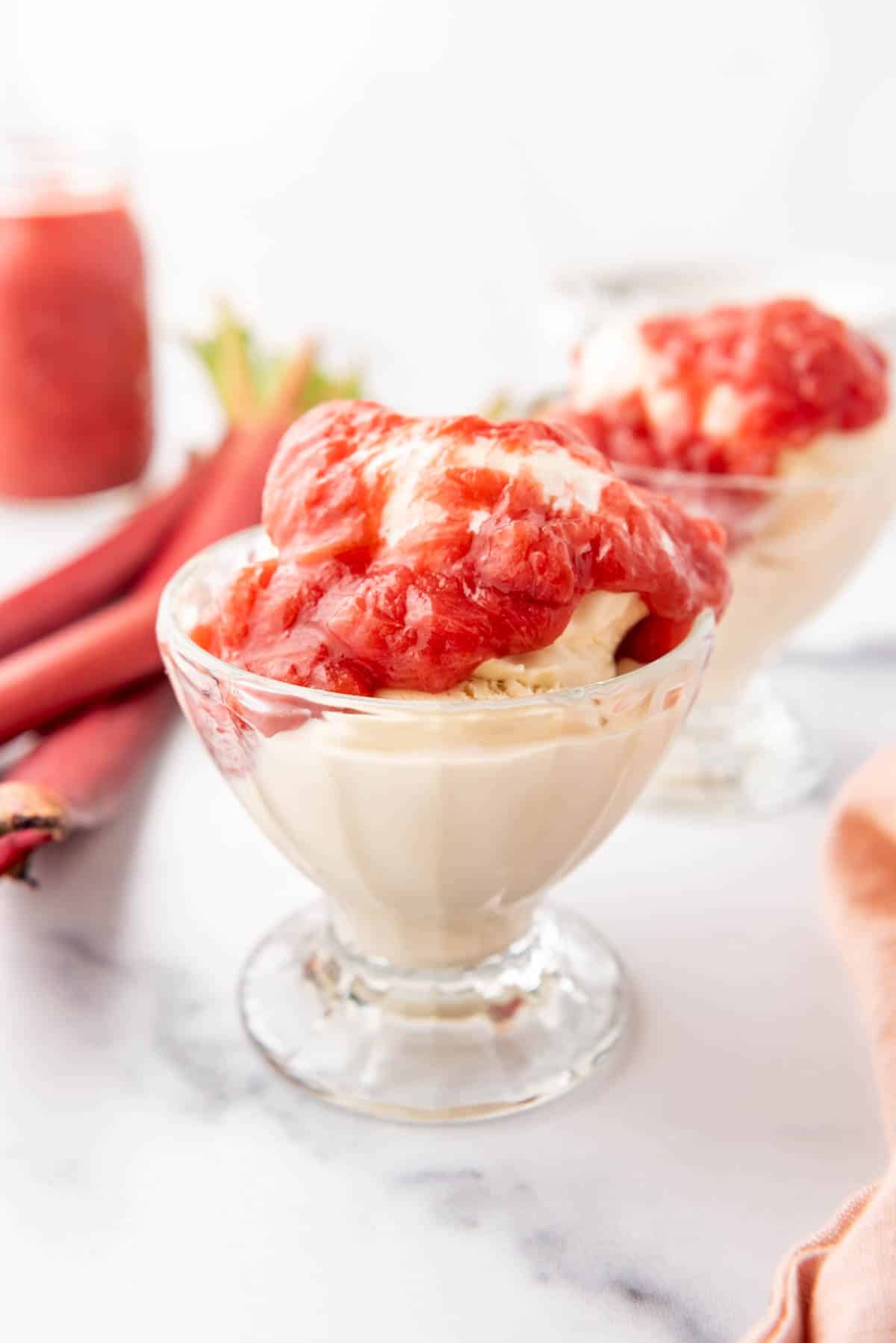 A cup of vanilla ice cream topped with warm rhubarb sauce.