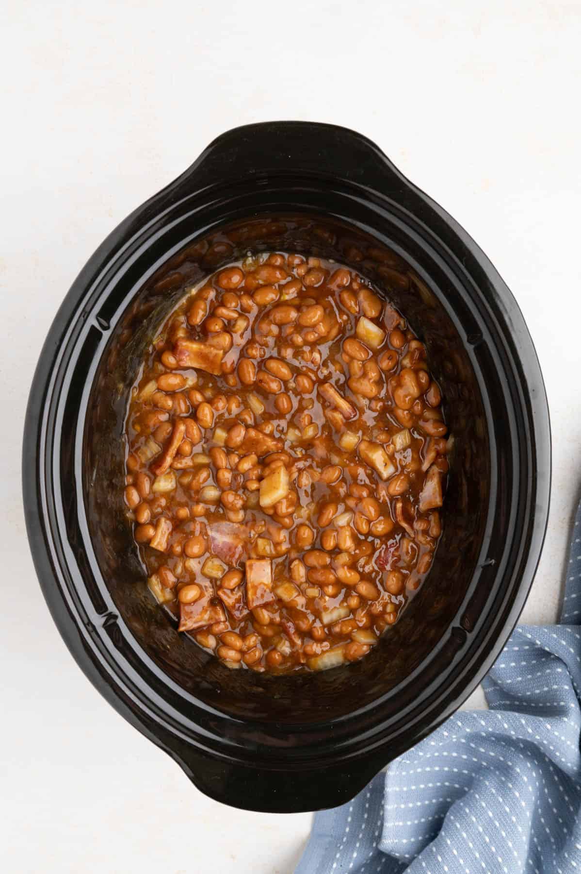 Ingredients for baked beans stirred together in a crockpot.