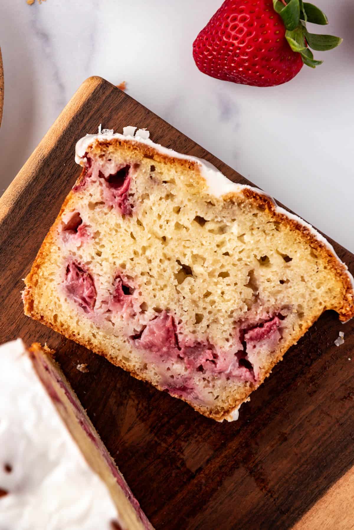 A slice of homemade strawberry bread on a wooden cutting board.