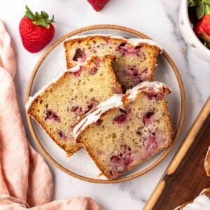 Slices of glazed strawberry bread on a plate.