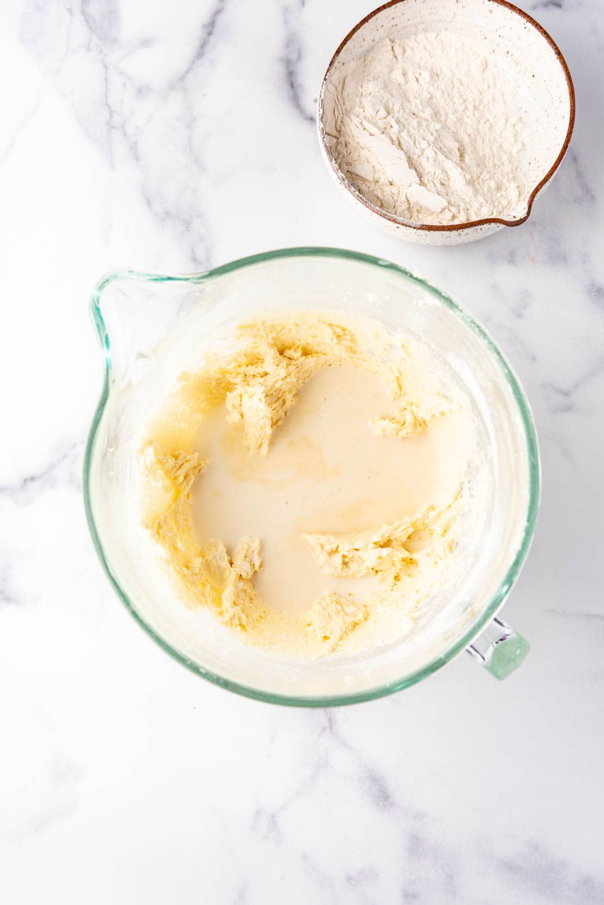 Adding milk alternately with flour to a glass mixing bowl for a white cake.