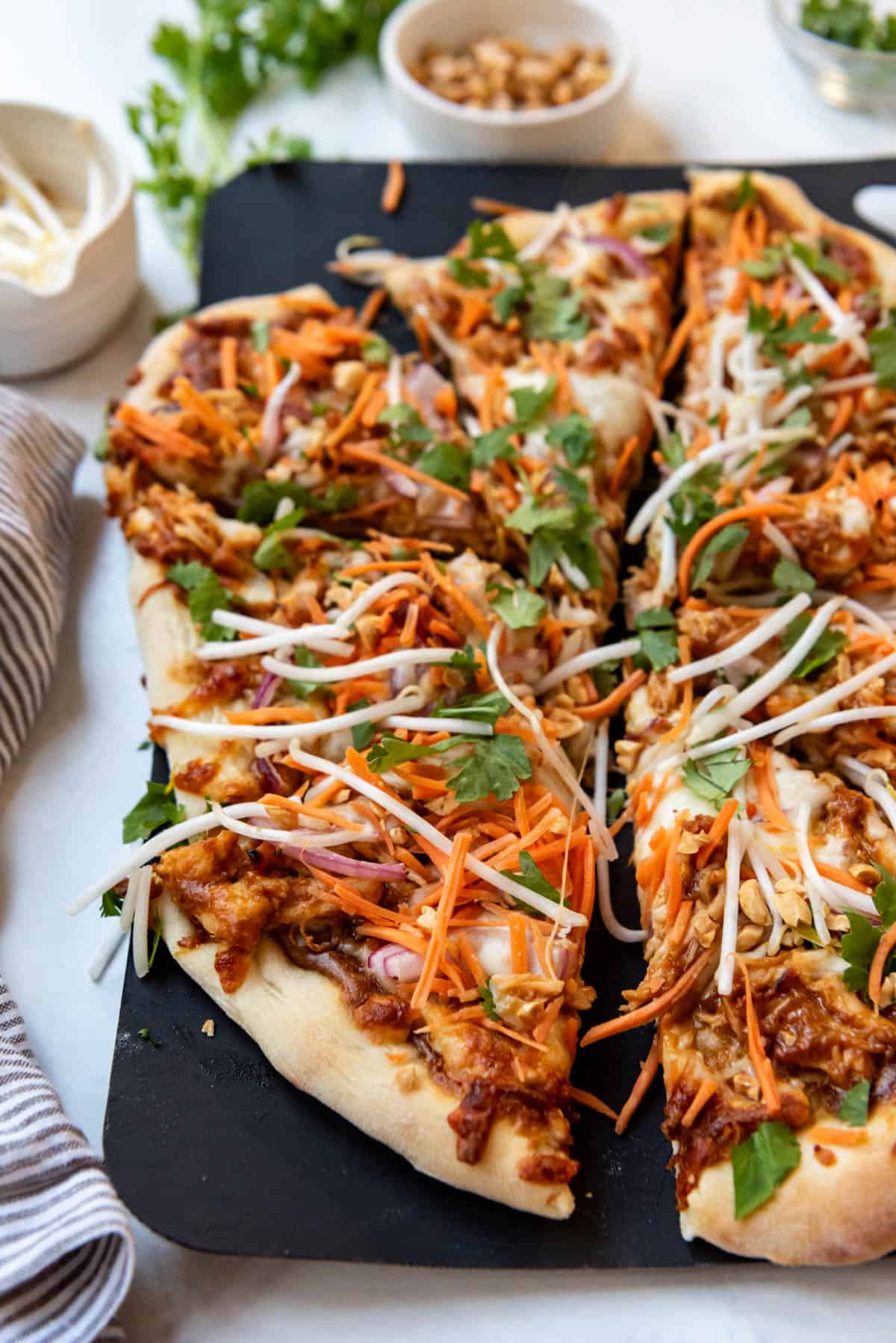 A close up image of slices of Thai chicken pizza.