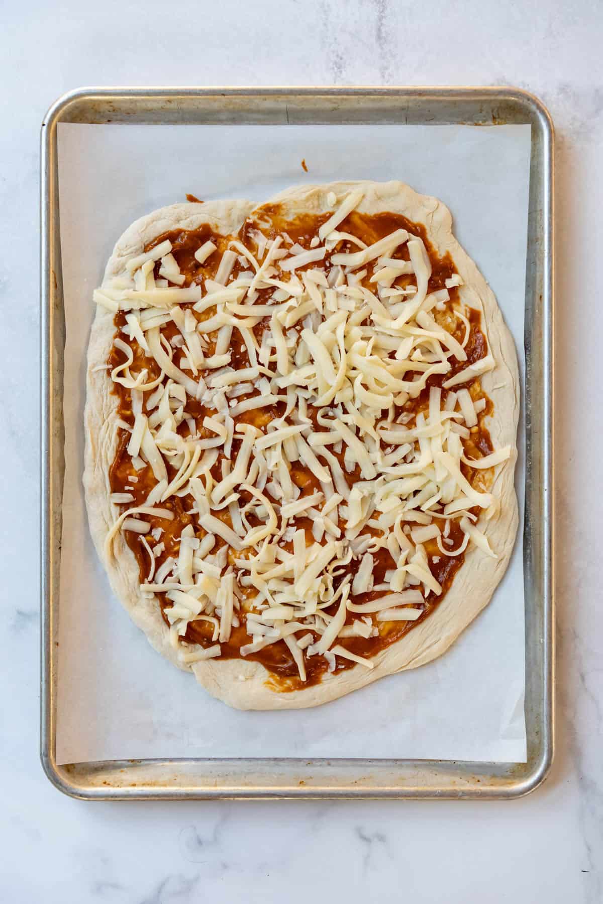 Sprinkling cheese on top of a pizza.