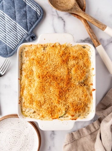 Baked zucchini casserole surrounded by kitchen items.