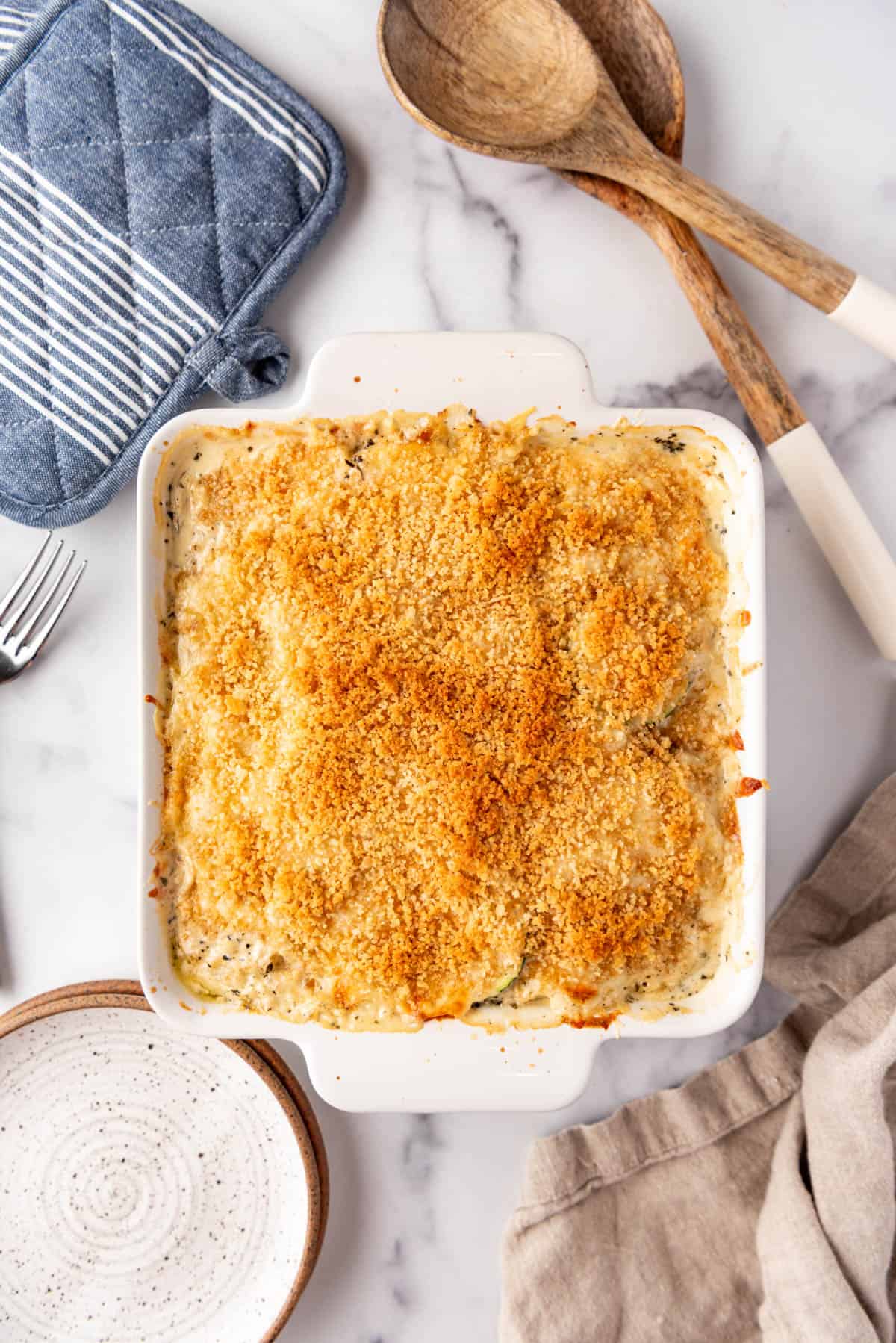 Baked zucchini casserole surrounded by kitchen items.