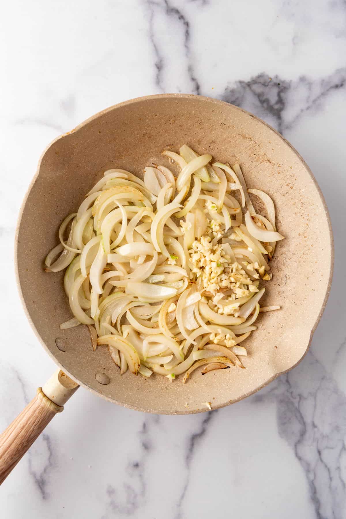 Sauteeing onions and garlic in butter in a pan.