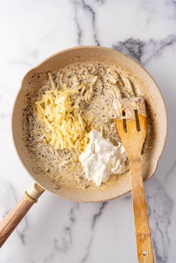 Adding cheese and sour cream to an herby onion sauce.