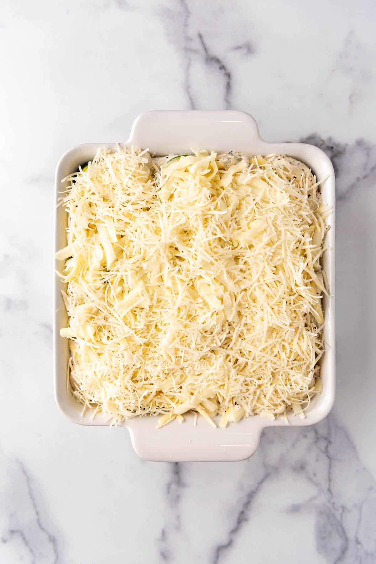 Shredded cheese sprinkled over a dish of zucchini casserole.