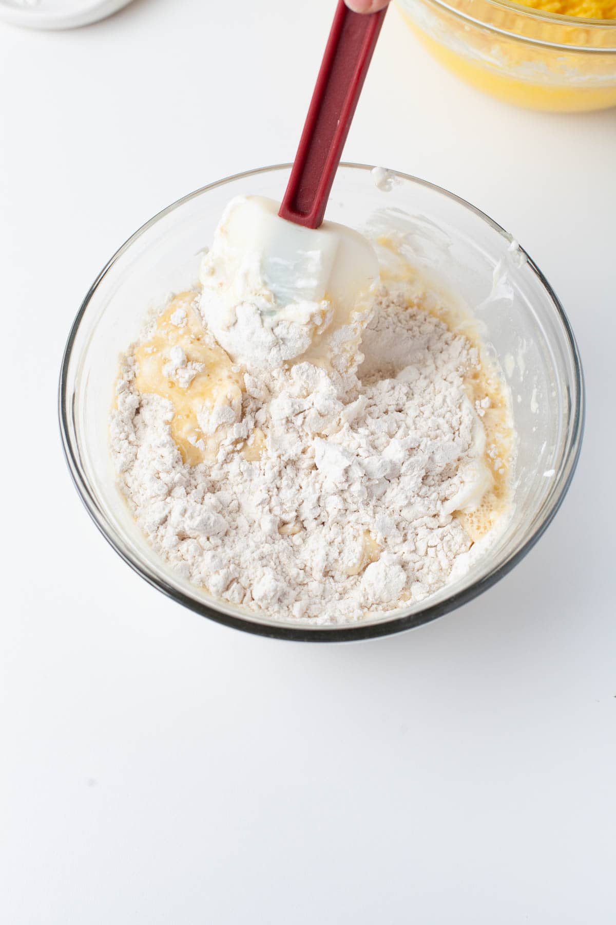 Close up image of flour, baking powder, sour cream and orange juice being mixed together in a mixing bowl.