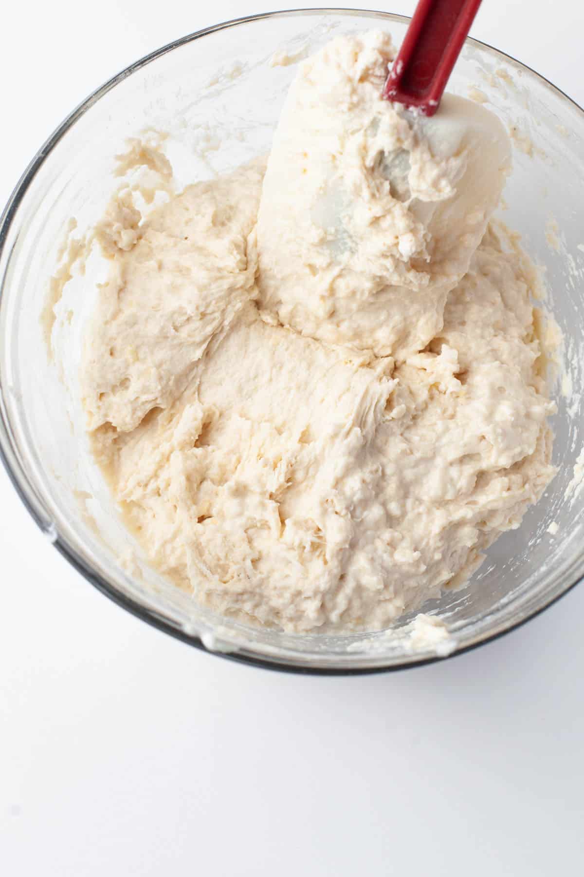 Close up image of flour, baking powder, sour cream, and orange juice being mixed together in a mixing bowl.