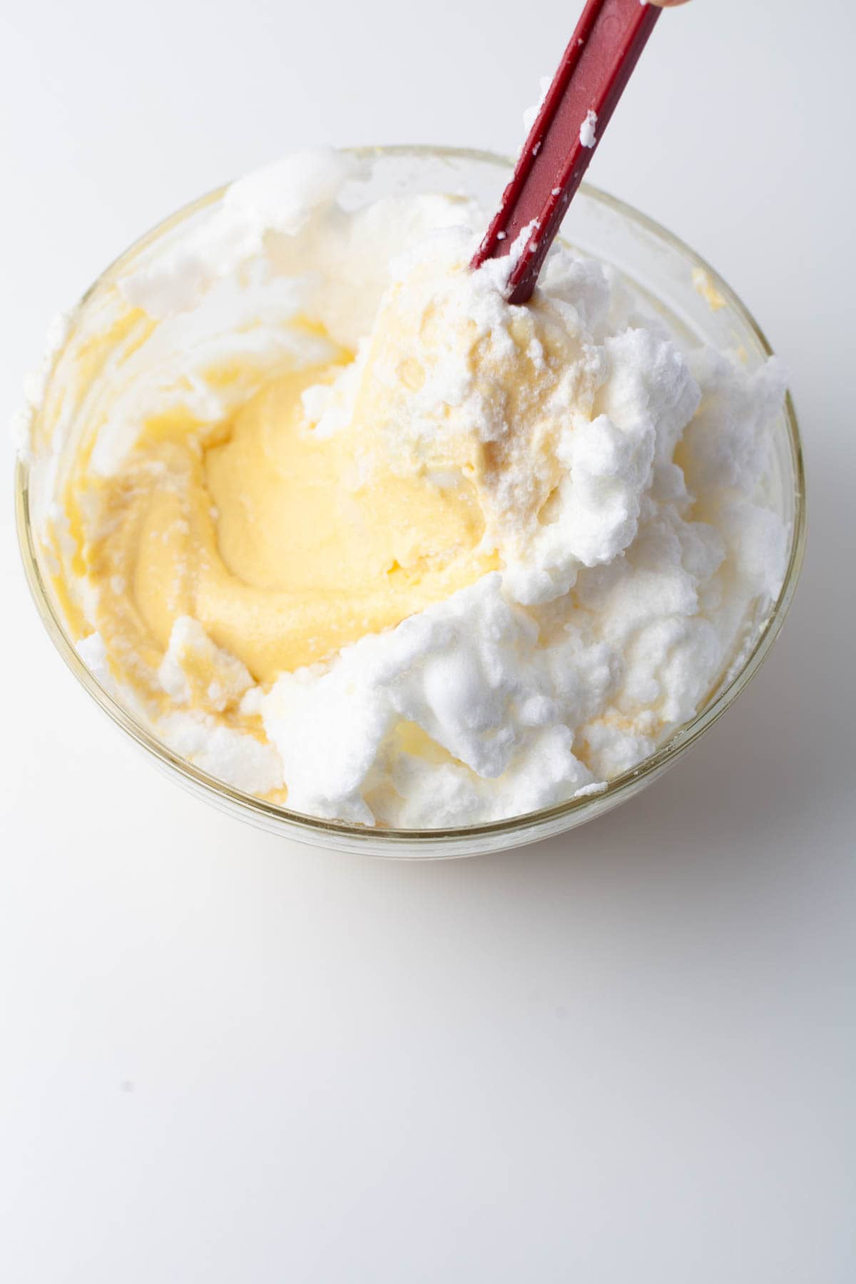 Overhead view of egg white mixture being incorporated into the orange loaf batter.