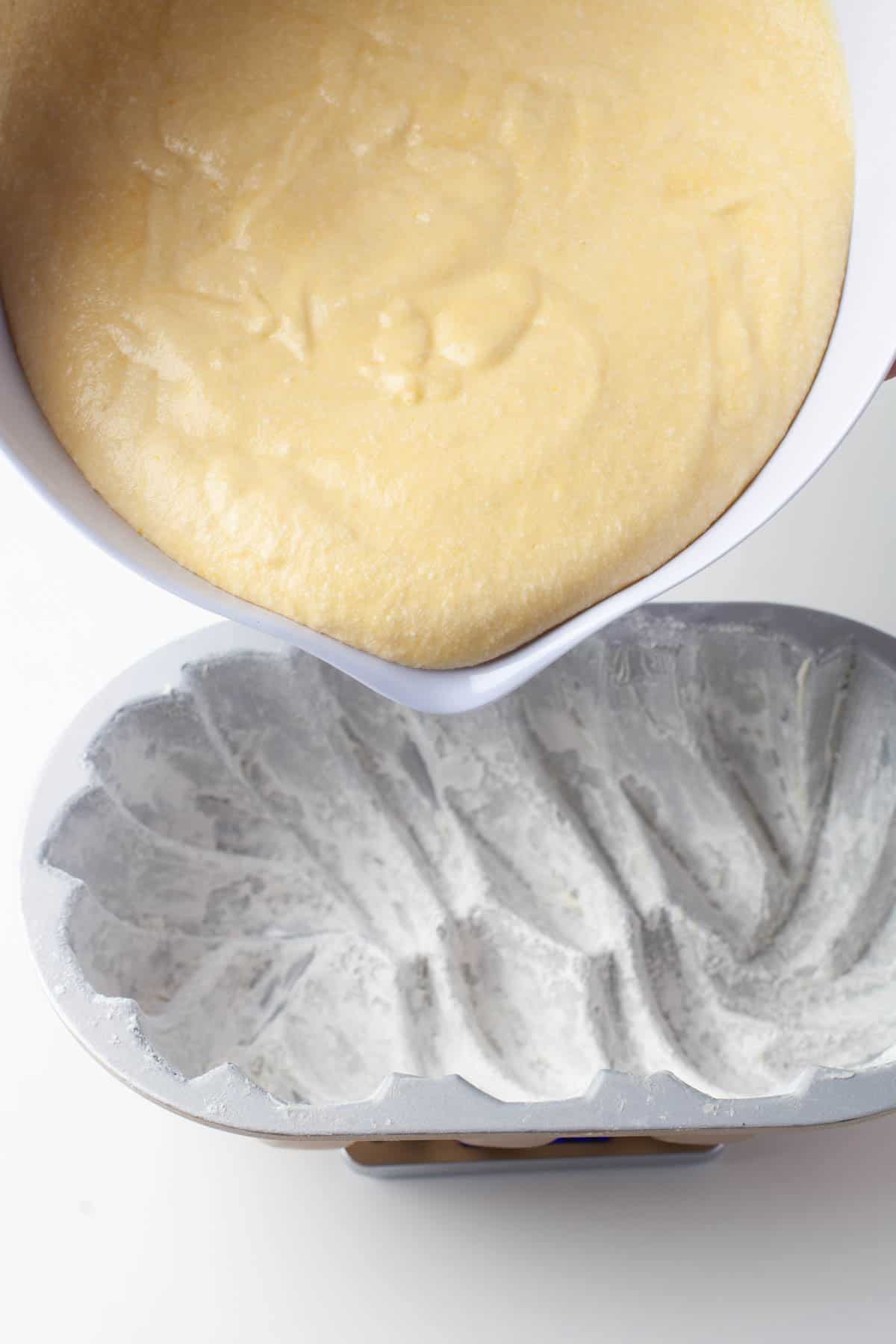 Close up view of batter being poured into a decorative loaf pan.