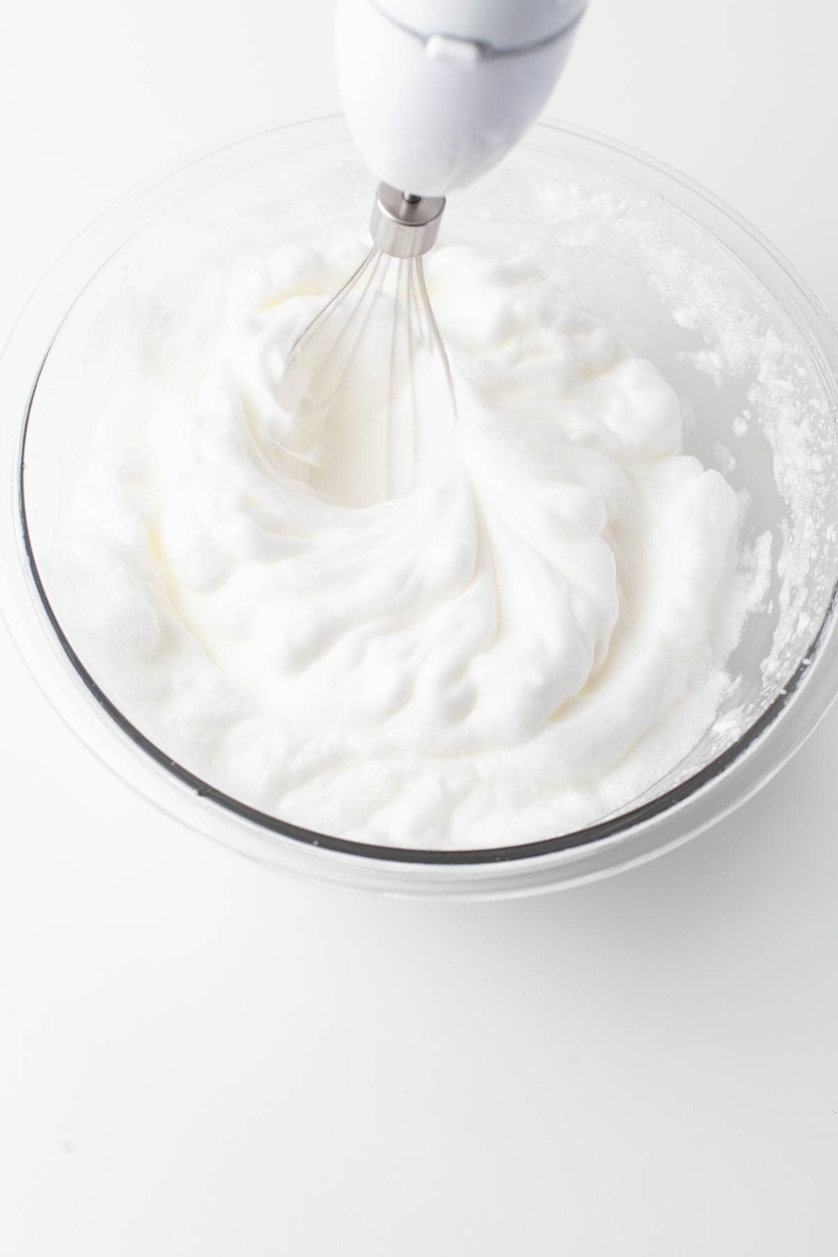 Close up view of egg whites being whisked.