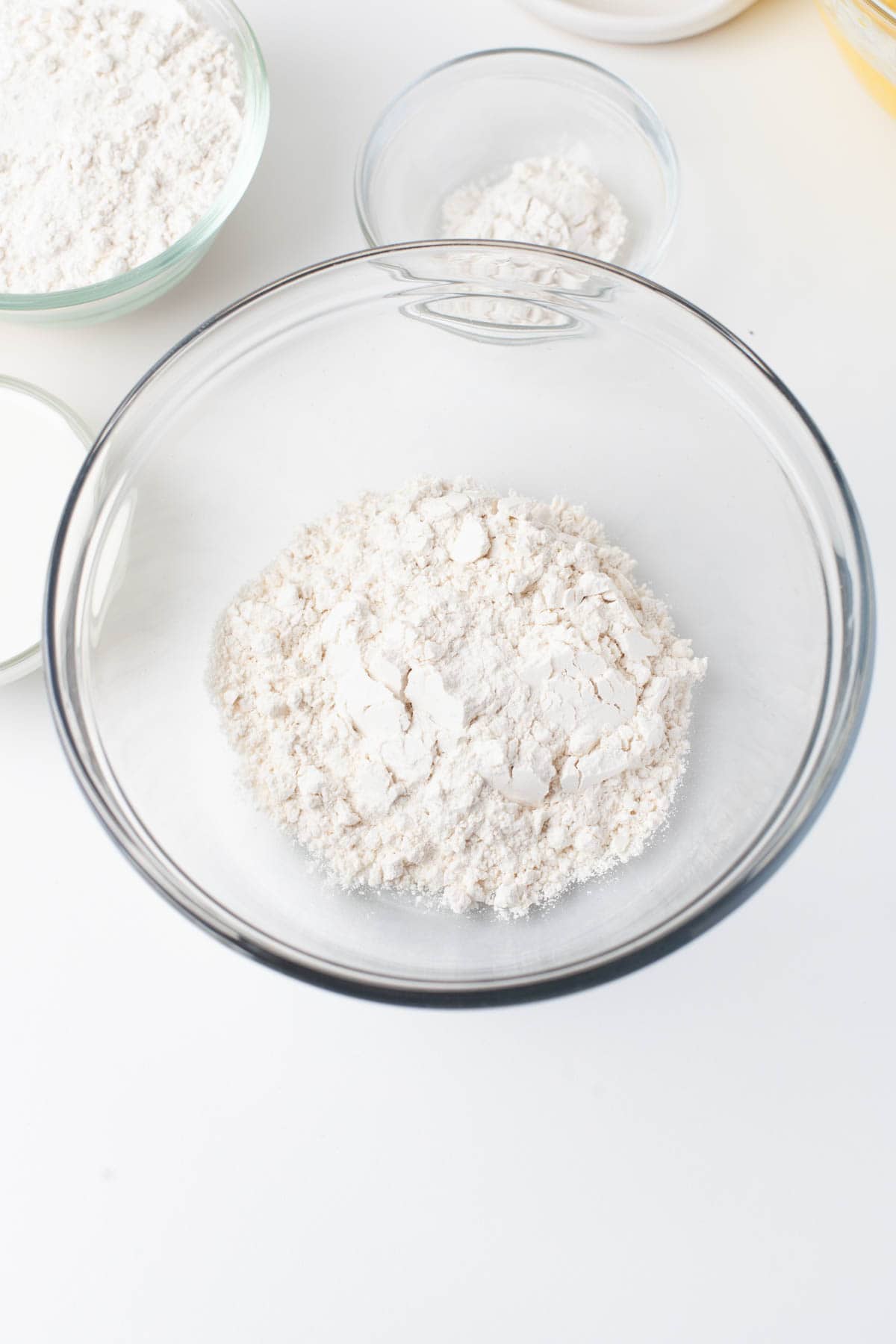 Overhead view of a glass mixing bowl with flour and baking powder in it.