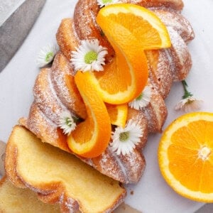 An overhead image of an orange loaf cake decorated with orange slices.