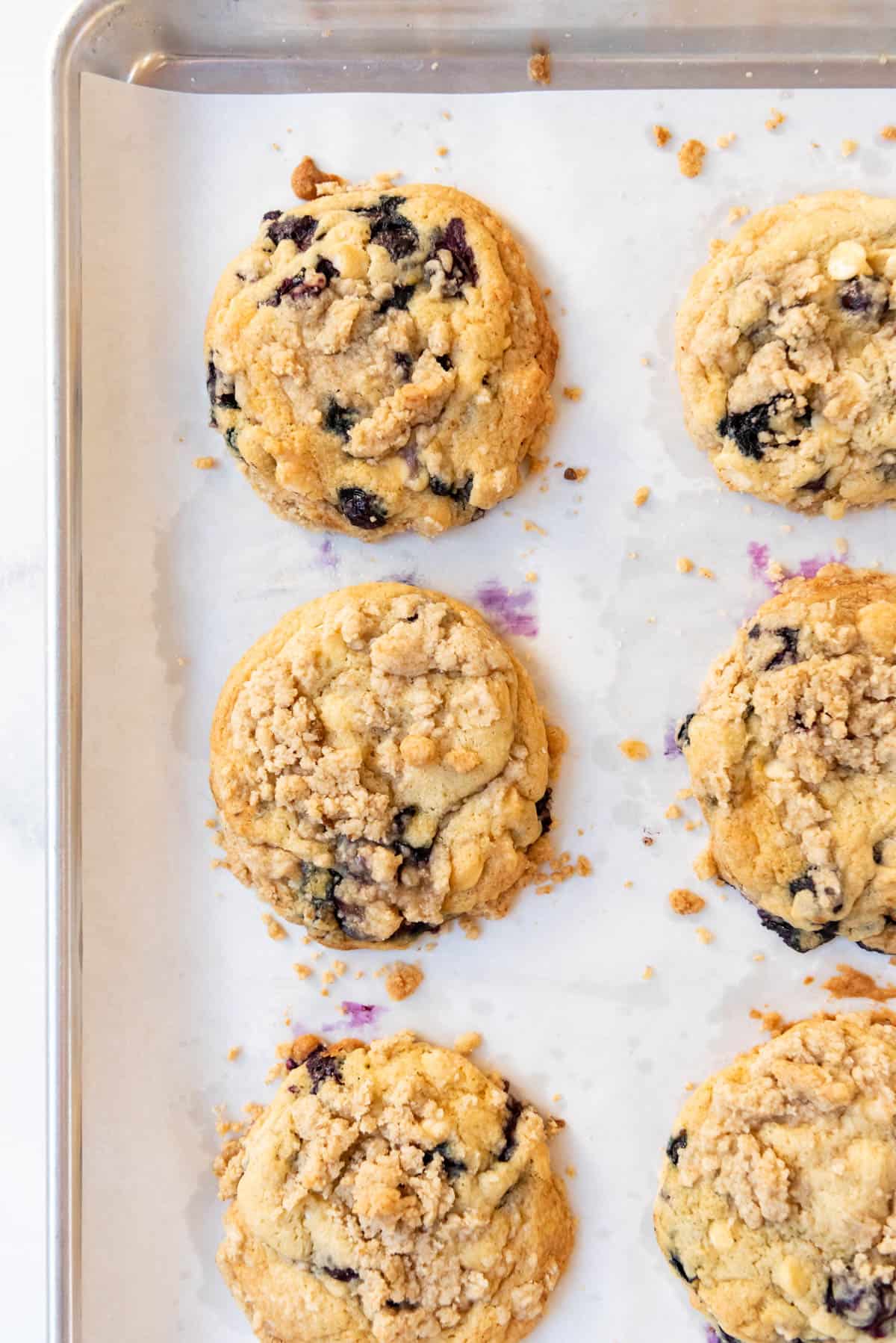 An overhead image of baked blueberry muffin cookies on parchment paper.