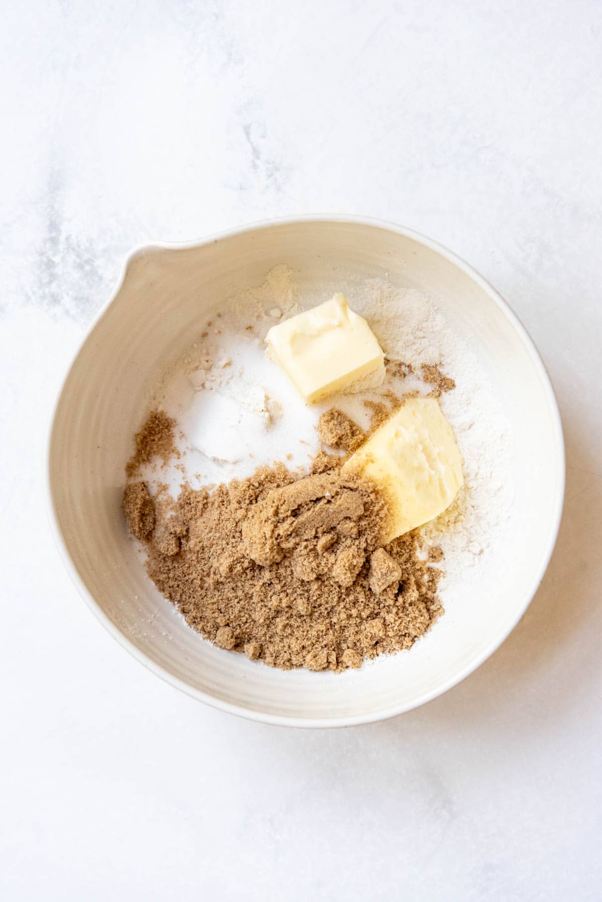 Combining butter, flour, and sugars in a bowl.