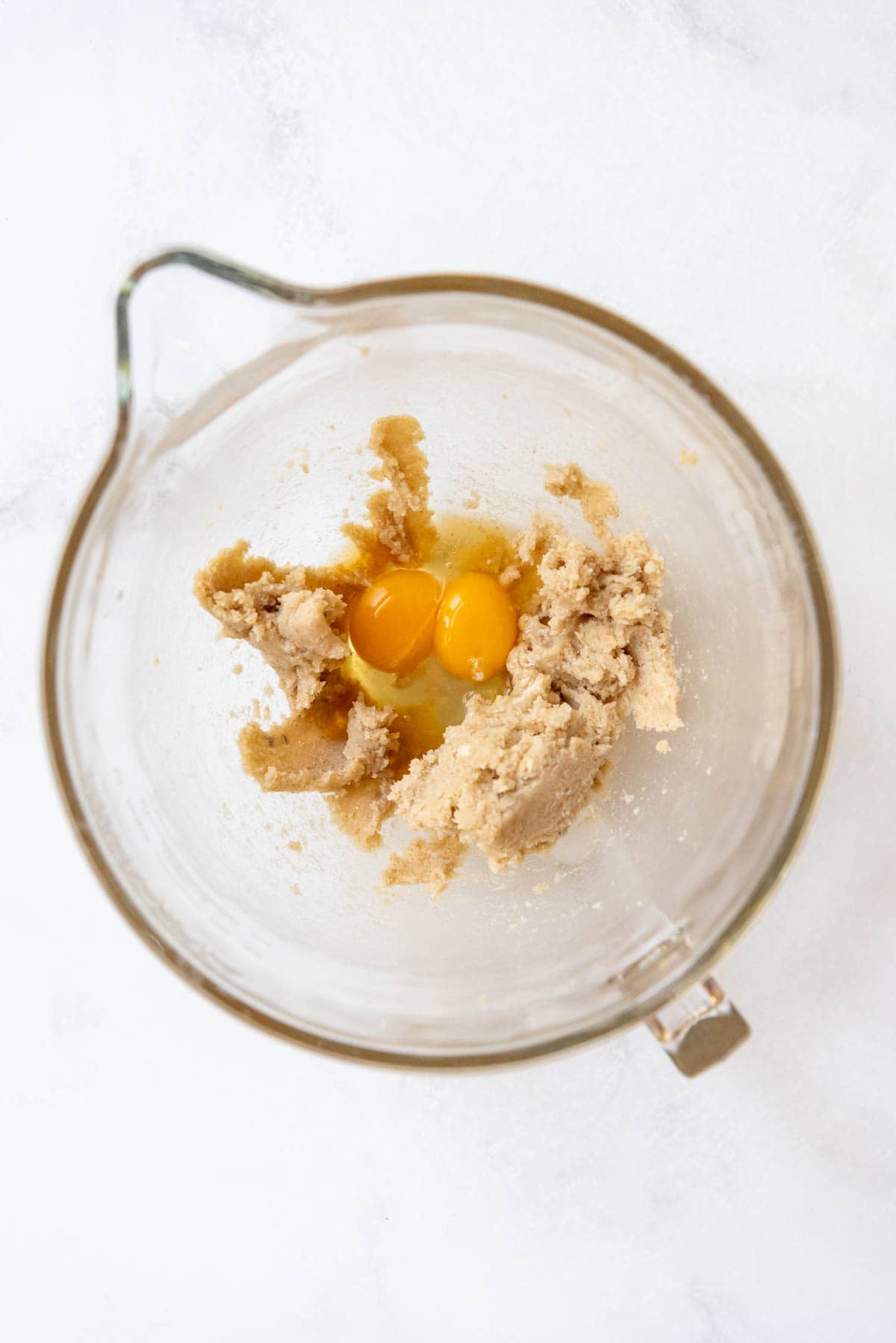 Adding eggs and vanilla to creamed butter and sugar in a mixing bowl.