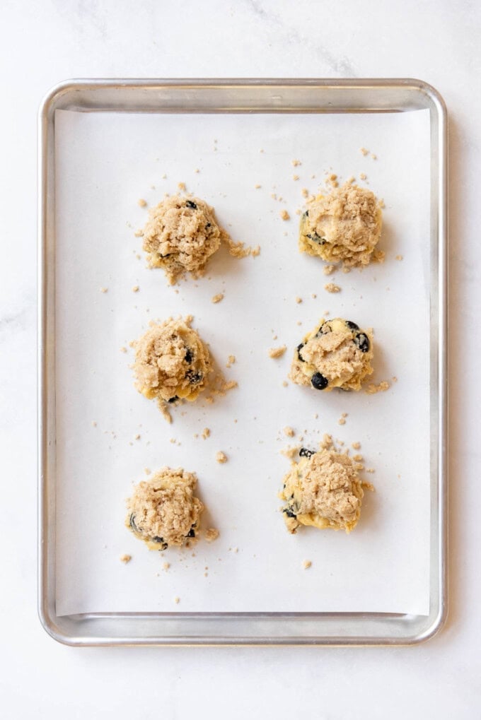 Blueberry muffin cookie dough on a baking sheet with crumb topping pressed on top.