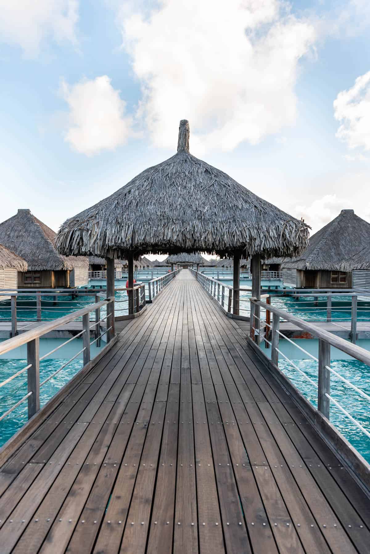 An image of a wooden walkway with a grass hut.