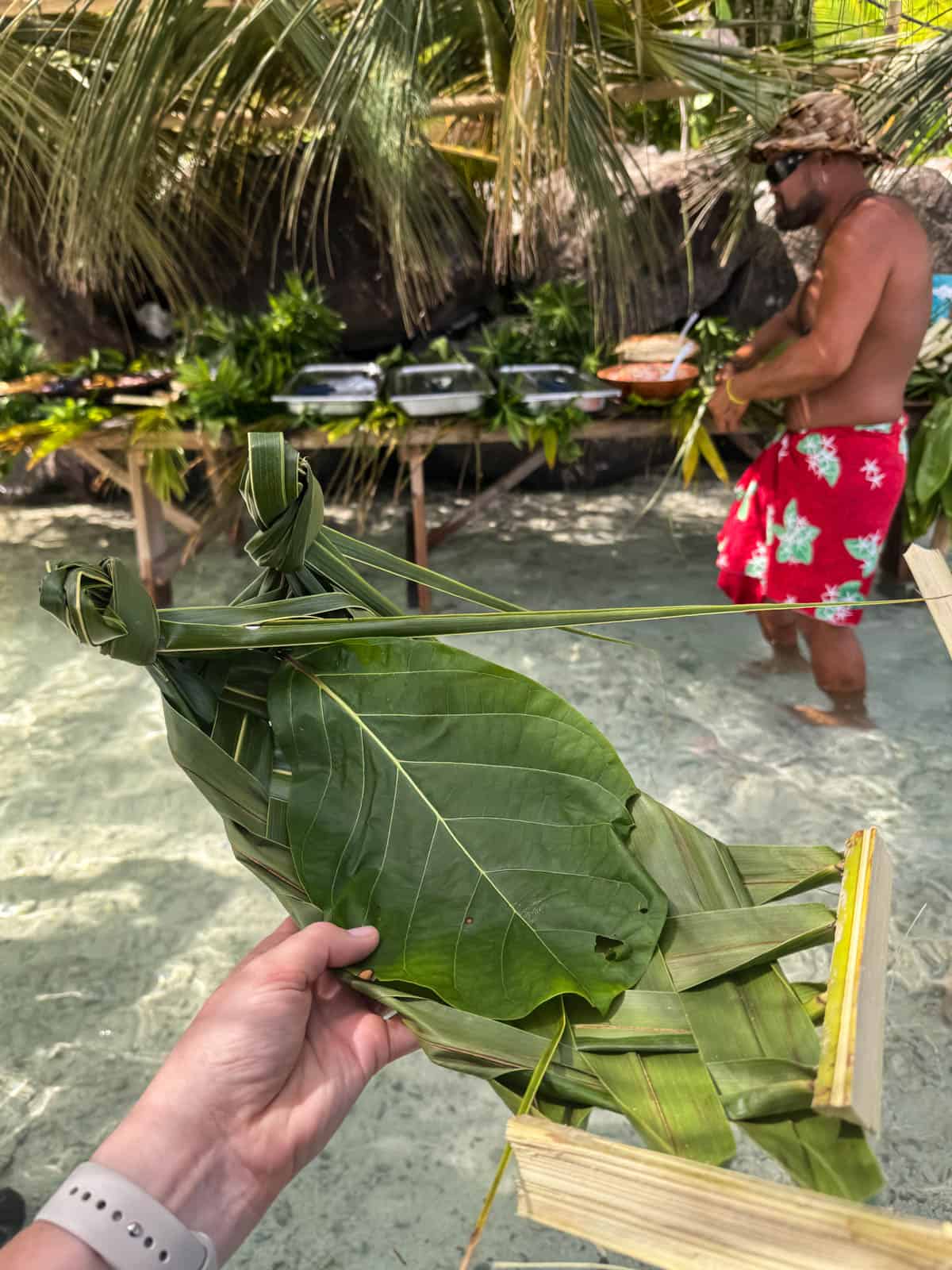 An image of a plate made from palm fronds and large leaves in front of a polynesian buffet in Bora Bora.