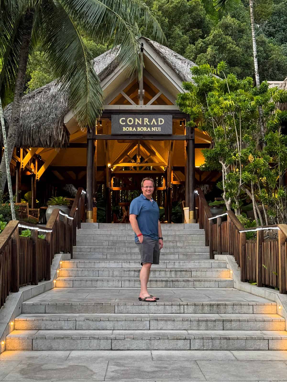 An image of a man on the steps of the Conrad resort in Bora Bora.