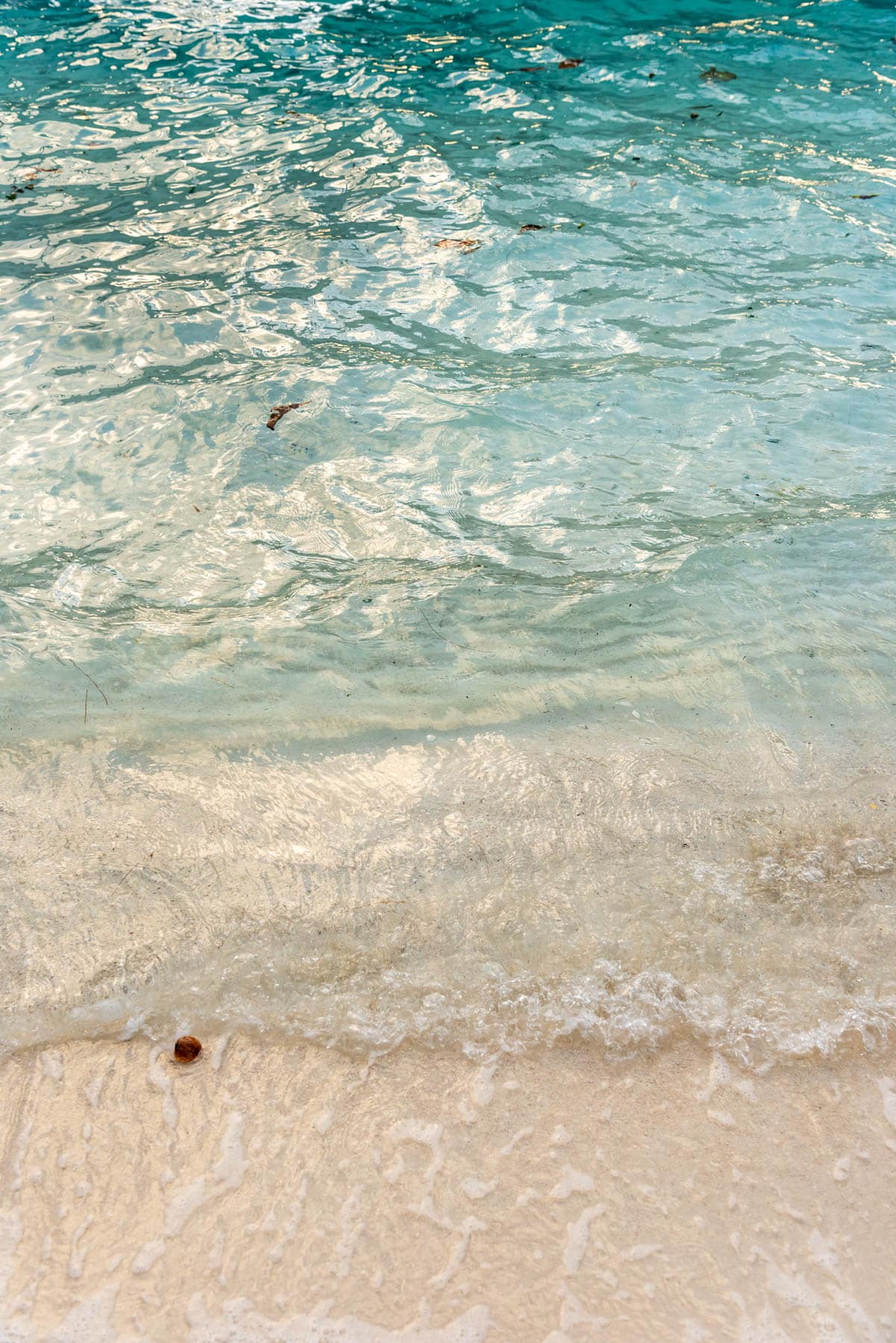 An image of gentle waves on a white sandy beach.