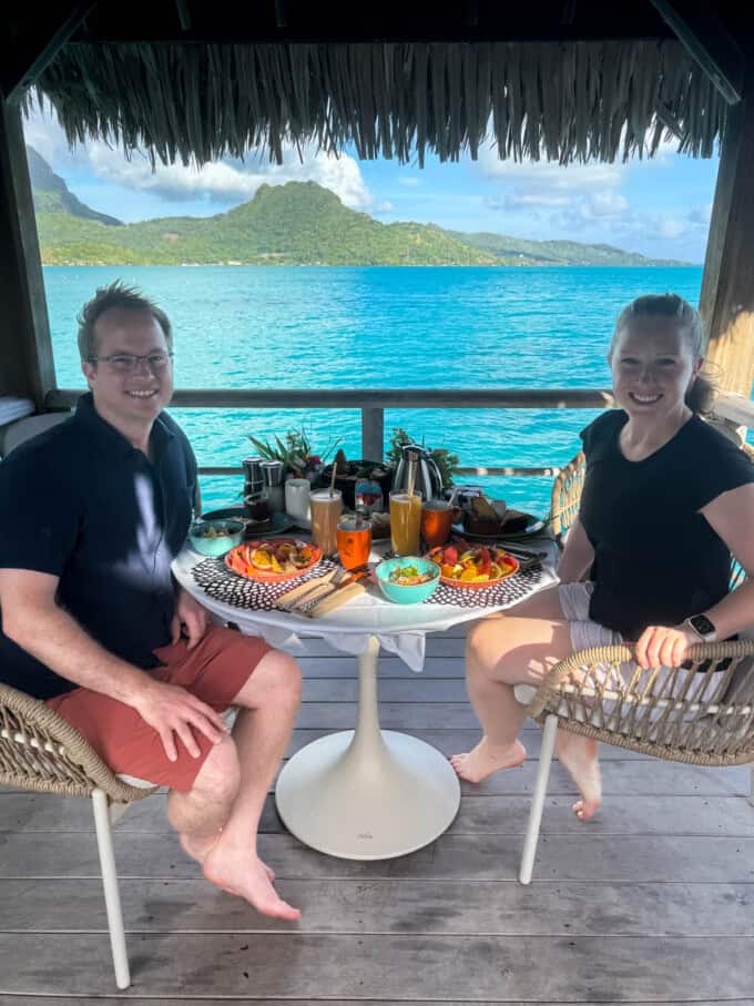 A couple sitting at a breakfast table on a private balcony at the St. Regis Bora Bora.