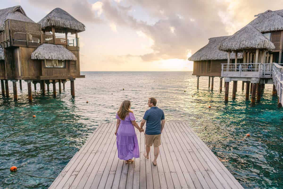 An image of a couple on a dock in front of the presidential suites at the Conrad Bora Bora Nui.