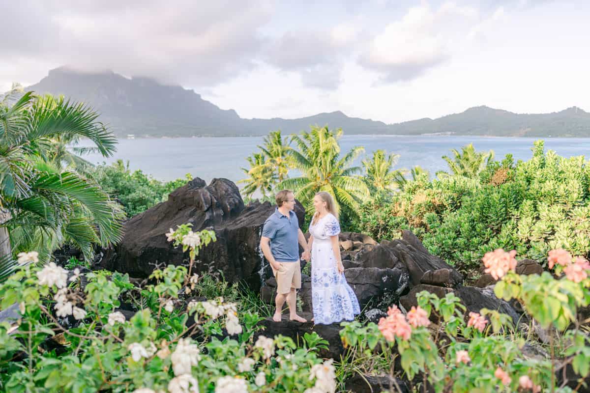 An image of a couple in Bora Bora on volcanic lava rock with tropical plants around.