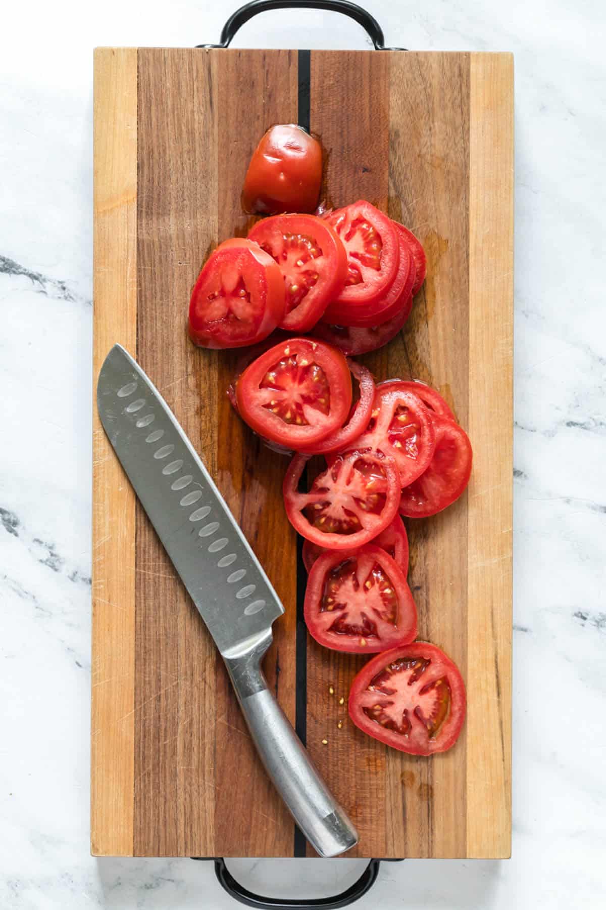 Sliced tomatoes on a cutting board with a knife.