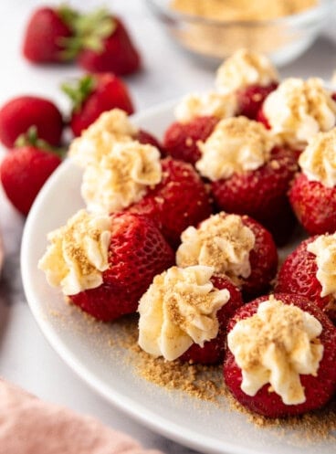 An image of cheesecake stuffed strawberries on a white plate.