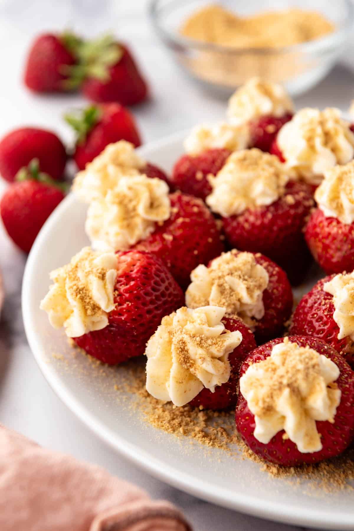 An image of cheesecake stuffed strawberries on a white plate.