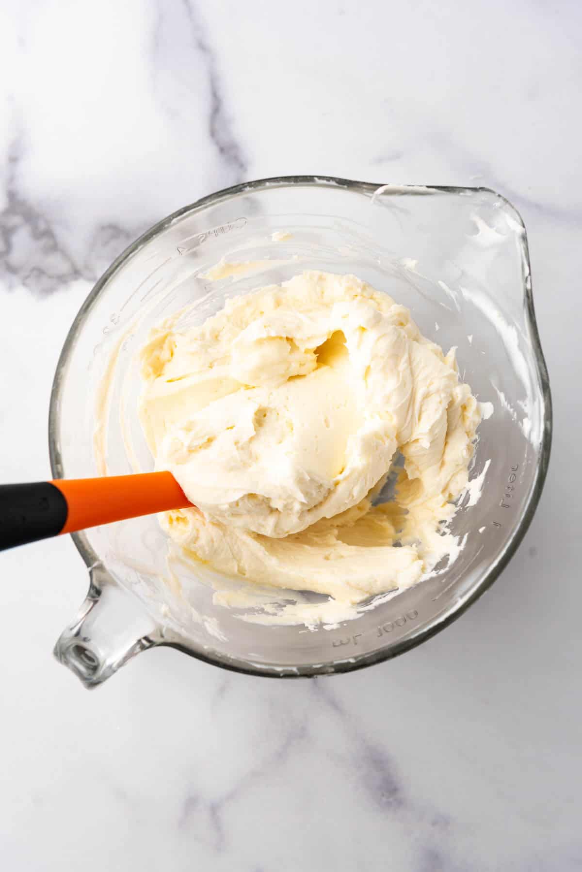 Creamy no-bake cheesecake filling in a glass mixing bowl.