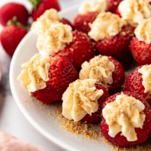 An image of cheesecake stuffed strawberries on a white plate.