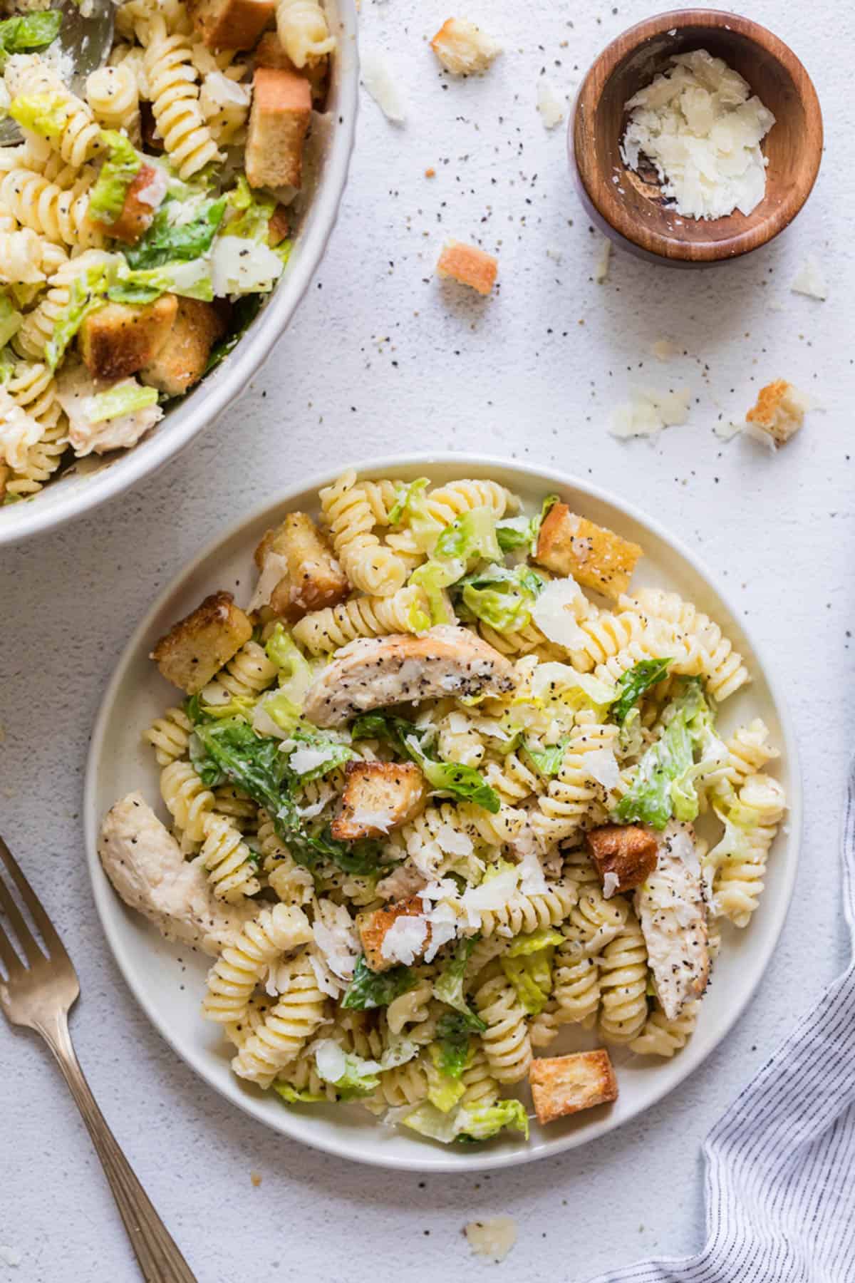 A plate of pasta salad with chicken, lettuce, and caesar salad dressing.