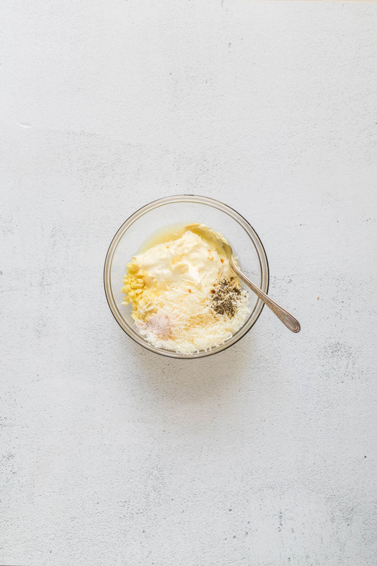 Combining ingredients for easy caesar salad dressing in a glass jar.