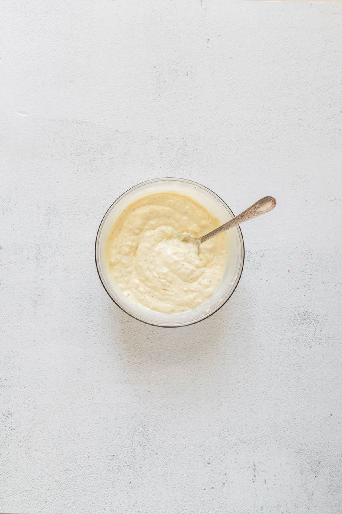 A jar of easy homemade caesar salad dressing with a spoon in it.