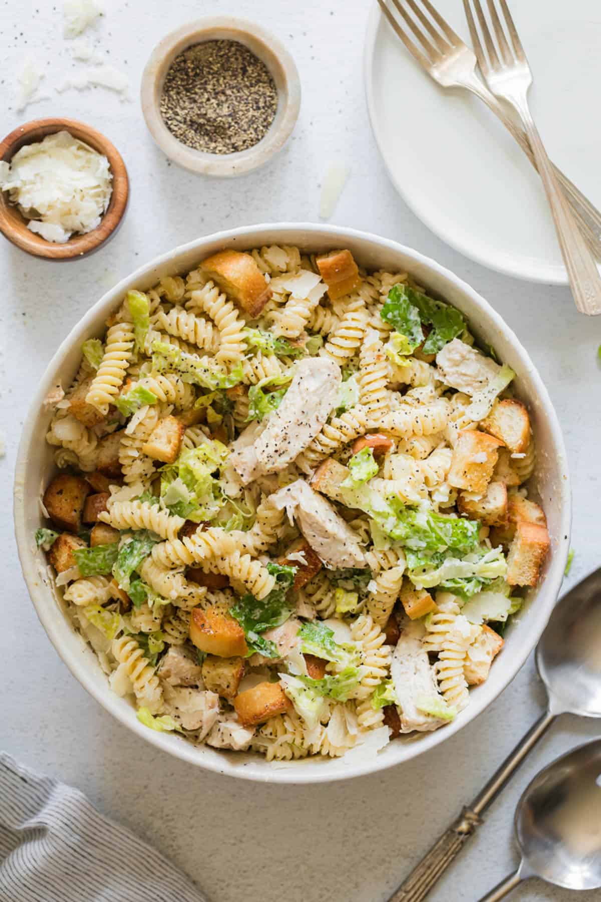 An overhead image of a bowl of chicken caesar pasta salad.