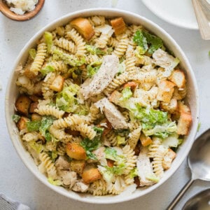 An overhead image of a bowl of chicken caesar pasta salad.