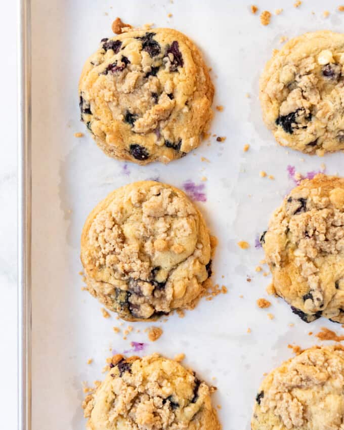 An overhead image of baked blueberry muffin cookies on parchment paper.